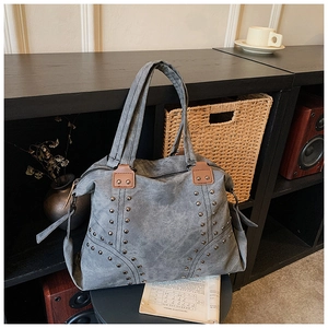 Detail of grey vintage tote bag with silver studs and brown leather handle accents
