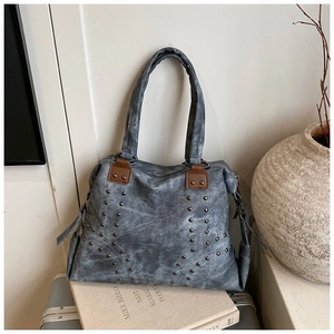 Detail of vintage grey tote bag featuring metal rivets and premium brown leather straps