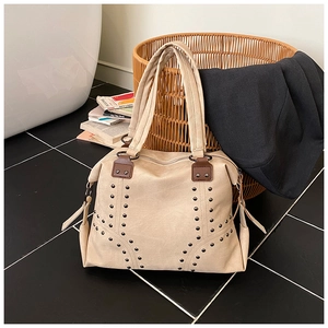 Close-up of beige tote bag with bronze rivets and premium textured leather detail
