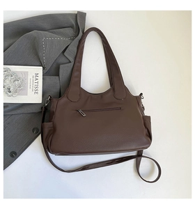Detail view of large dark brown leather tote bag with functional pockets and shoulder strap
