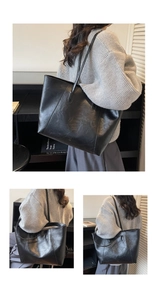 Close-up of black leather tote bag featuring sleek panel stitching and shoulder strap details