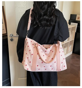 Detail of strawberry print travel bag showing the waffle fabric and pink leather straps