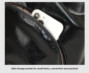 Close-up of side zipper pocket on black glossy leather bag holding a smartphone