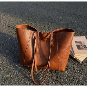 Detail of vintage textured brown faux leather tote bag on asphalt background