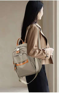 Detail of khaki nylon backpack featuring multiple zip pockets and adjustable straps