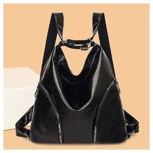 Detail of black glossy faux leather backpack featuring decorative metal zippers and top handle
