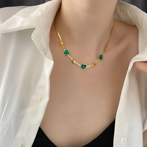 Emerald heart pendant necklace featuring gold-plated snake chain shown on female model
