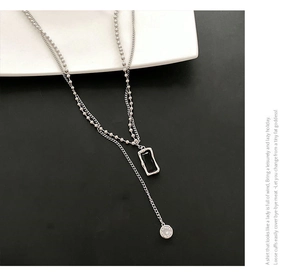 Detail of layered silver chain necklace with a black rectangular pendant and small crystal