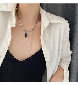 Detail of layered silver chain necklace featuring a rectangular black stone pendant