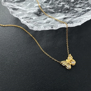 Collier luxueux avec pendentif papillon doré et cristaux sur une surface texturée noire
