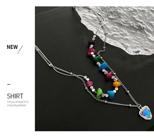 Détail du collier à plusieurs rangs avec perles colorées et pendentif cœur en gemme