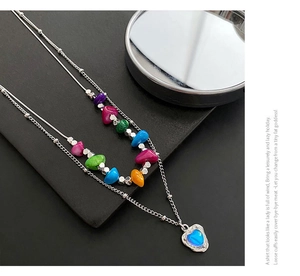 Gros plan d'un collier double couche avec perles colorées et pendentif cœur bleu