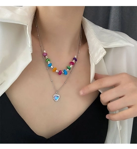 Détail du collier de perles colorées avec pendentif cœur bleu irisé sur modèle
