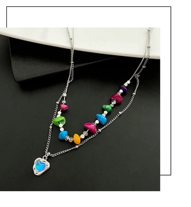 Détail du collier double rang avec perles colorées et pendentif en forme de cœur bleu