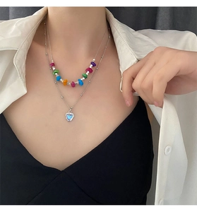 Détail d'un collier à deux rangs avec perles colorées et pendentif cœur bleu texturé