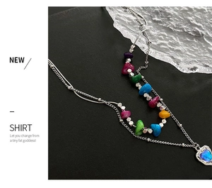 Détail d'un collier double épaisseur avec perles colorées et pendentif cœur bleu