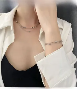 Detailed view of layered titanium steel necklace and bracelet with smooth metal beads
