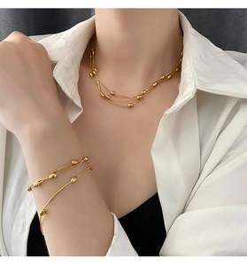Model wearing multi-layer gold titanium steel beaded necklace and bracelet set
