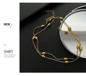 Detailed view of double layered gold snake chain necklace with small metal beads
