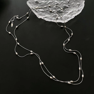 Double-layered silver snake chain necklace with metallic beads on black background