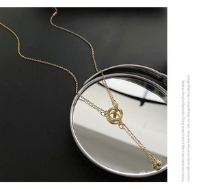 Dettaglio della collana con pendente a doppio anello d'oro intrecciato e pavé di cristalli