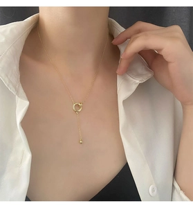 Dettaglio della collana a Y dorata con anelli intrecciati e nappa sottile elegante
