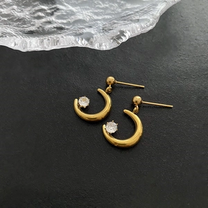 Minimalist gold moon-shaped earrings with sparkling cubic zirconia on black background