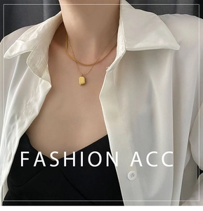 Detail of a double-layered gold titanium necklace with a solid rectangular pendant on model
