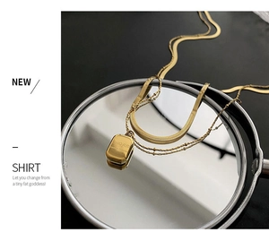 Close-up of double-layered gold titanium necklace with square pendant and flat snake chain
