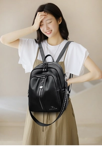 Detail of black lychee grain leather backpack with metallic logo and woven strap