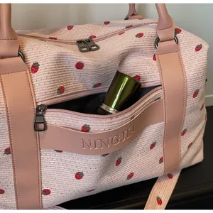 Detail of pink strawberry corduroy travel bag showing large front pocket and leather trim