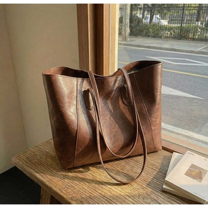Detailed texture of brown faux leather tote bag on wooden stool with natural sunlight