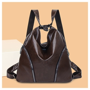 Detail view of the brown PU leather backpack texture and side zipper on a warm background