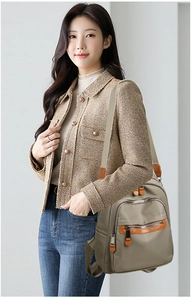 Detail of khaki waterproof nylon backpack with brown leather trim and multi-pocket design