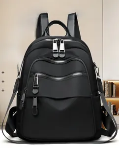 Detail view of the black nylon backpack showing silver zippers and waterproof fabric