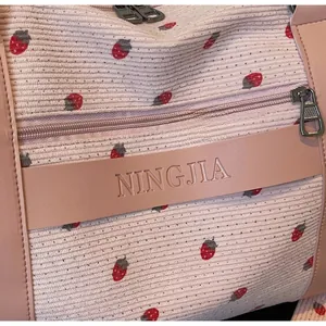 Detail of pink corduroy fabric with strawberry embroidery and leather brand tag