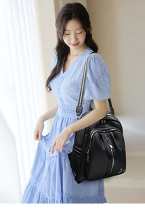 Detail of black lychee grain leather backpack with geometric pattern shoulder strap