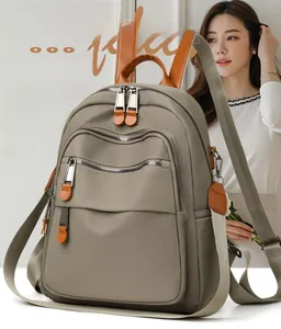 Detail of grey waterproof nylon backpack with brown leather handles and zipper pockets