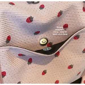 Detail of pink strawberry corduroy travel bag showing secure magnetic buckle closure