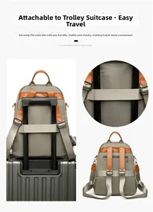 Grey travel backpack with luggage strap detail showing attachment to a suitcase handle