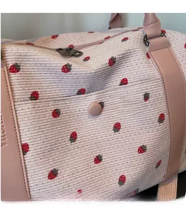 Close-up of pink corduroy fabric with strawberry print and leather handle detail