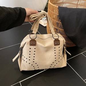 Cream canvas tote bag with V-shaped rivets and leather patches for a retro casual look