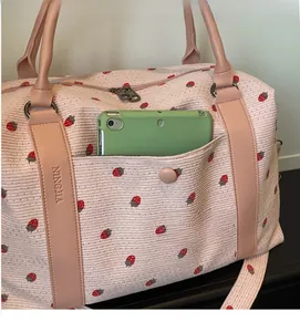 Close-up of pink corduroy strawberry travel bag front pocket with a green tablet inside