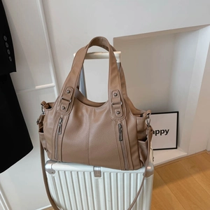 Brown large capacity tote bag with lychee texture on a white suitcase for travel