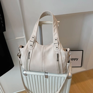 Large off-white tote bag with lychee texture and side pockets on a suitcase