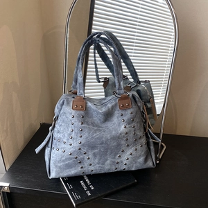 Blue denim style tote bag with silver studs and brown leather handles in studio setting