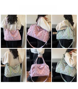 Detail view of large corduroy travel bags with strawberry print in pink and green