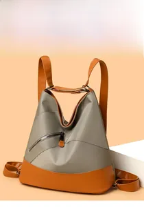 Dettaglio dello zaino in nylon grigio con accenti in pelle arancione e tasca con zip obliqua