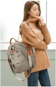 Close-up of waterproof nylon backpack featuring leather pulls and multiple zip pockets