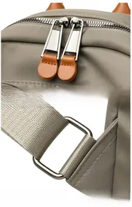 Detail of high-quality nylon backpack featuring dual zippers with leather pulls and metal buckles